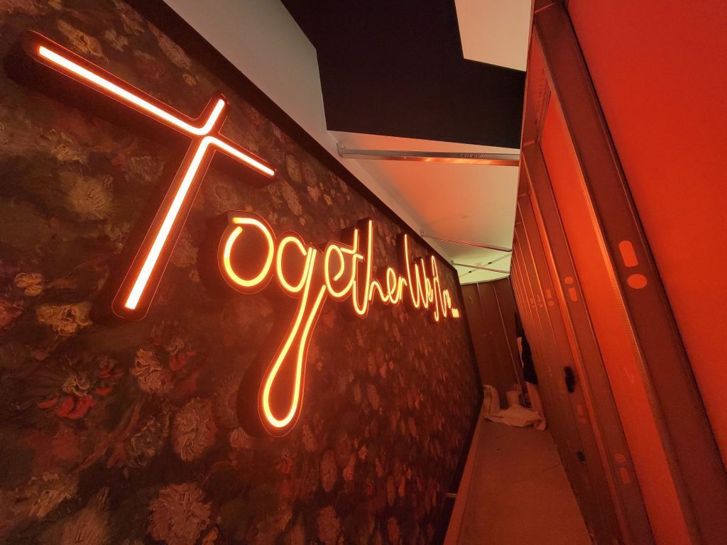 LED neon-flex lettering glowing on a floral feature wall